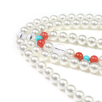 Pearl meditation bracelet with red and blue beads on a white background