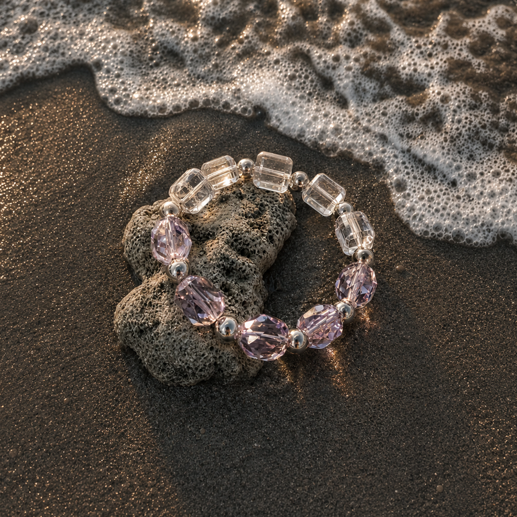 Chrysaora Colorata bracelet with purple and clear beads on a beach with waves.