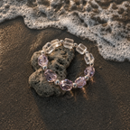 Chrysaora Colorata bracelet with purple and clear beads on a beach with waves.