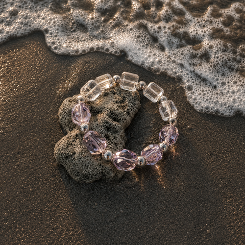 Chrysaora Colorata bracelet with purple and clear beads on a beach with waves.