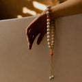 Hand holding the Concentration + Strength Meditation Bracelet, a beaded bracelet with a neutral background