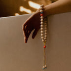 Hand holding the Concentration + Strength Meditation Bracelet, a beaded bracelet with a neutral background