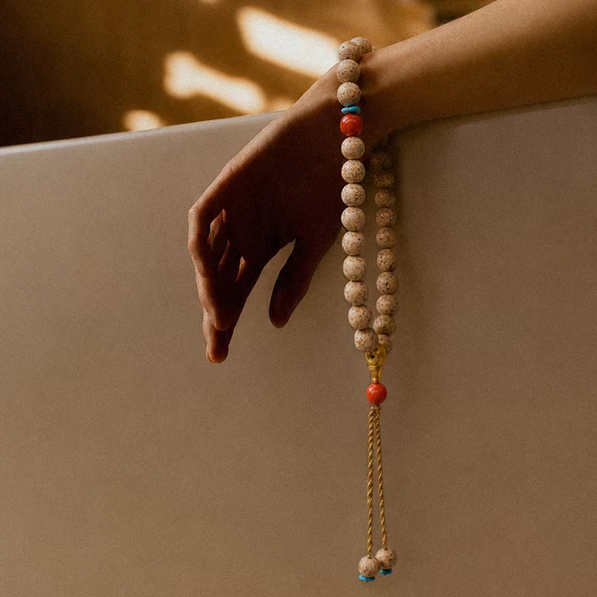Hand holding the Concentration + Strength Meditation Bracelet, a beaded bracelet with a neutral background