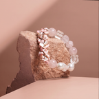 Bracelet with pink and clear beads on a stone surface against a beige background