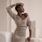 Handcrafted pink quartz and pearl bead bracelet with a floral charm, worn by a model in a taupe ribbed knit wrap dress.