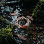 Flamingo bracelet with gemstones and red stone in a natural setting with water and moss