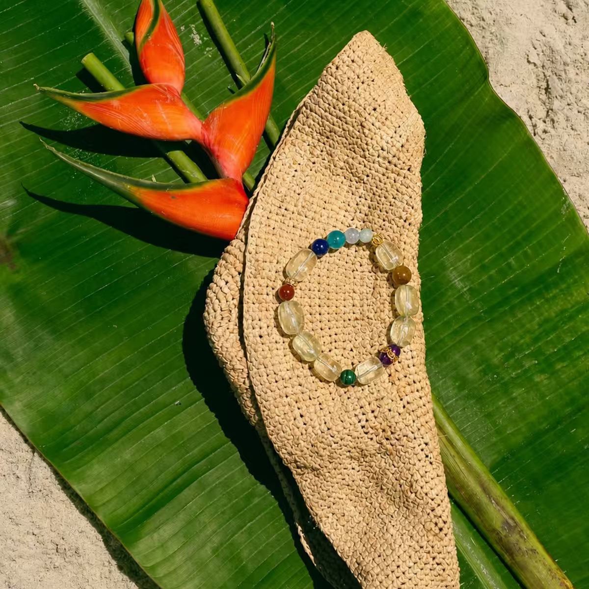 Parrot bracelet on a woven sandal with a tropical leaf and flower in the background