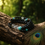 Black beaded bracelet with turquoise beads on a wooden branch with a peacock feather.
