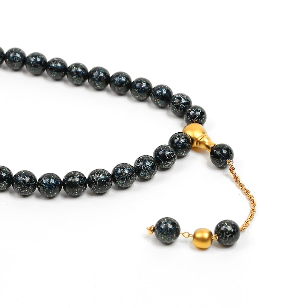 Close-up of blue blackwood meditation beads with brass tassel detail