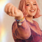 Person with pink hair wearing a colorful beaded bracelet on a blurred background