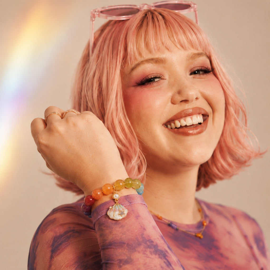 Woman with pink hair and colorful bracelets smiling against a neutral background