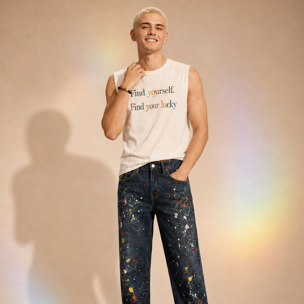Person wearing a sleeveless shirt with text and colorful jeans against a beige background