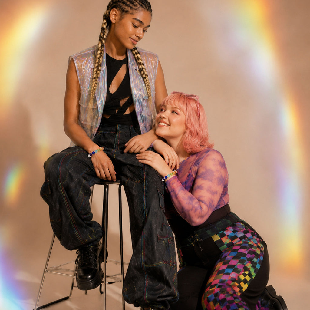 Two people sitting on a stool with a rainbow effect in the background