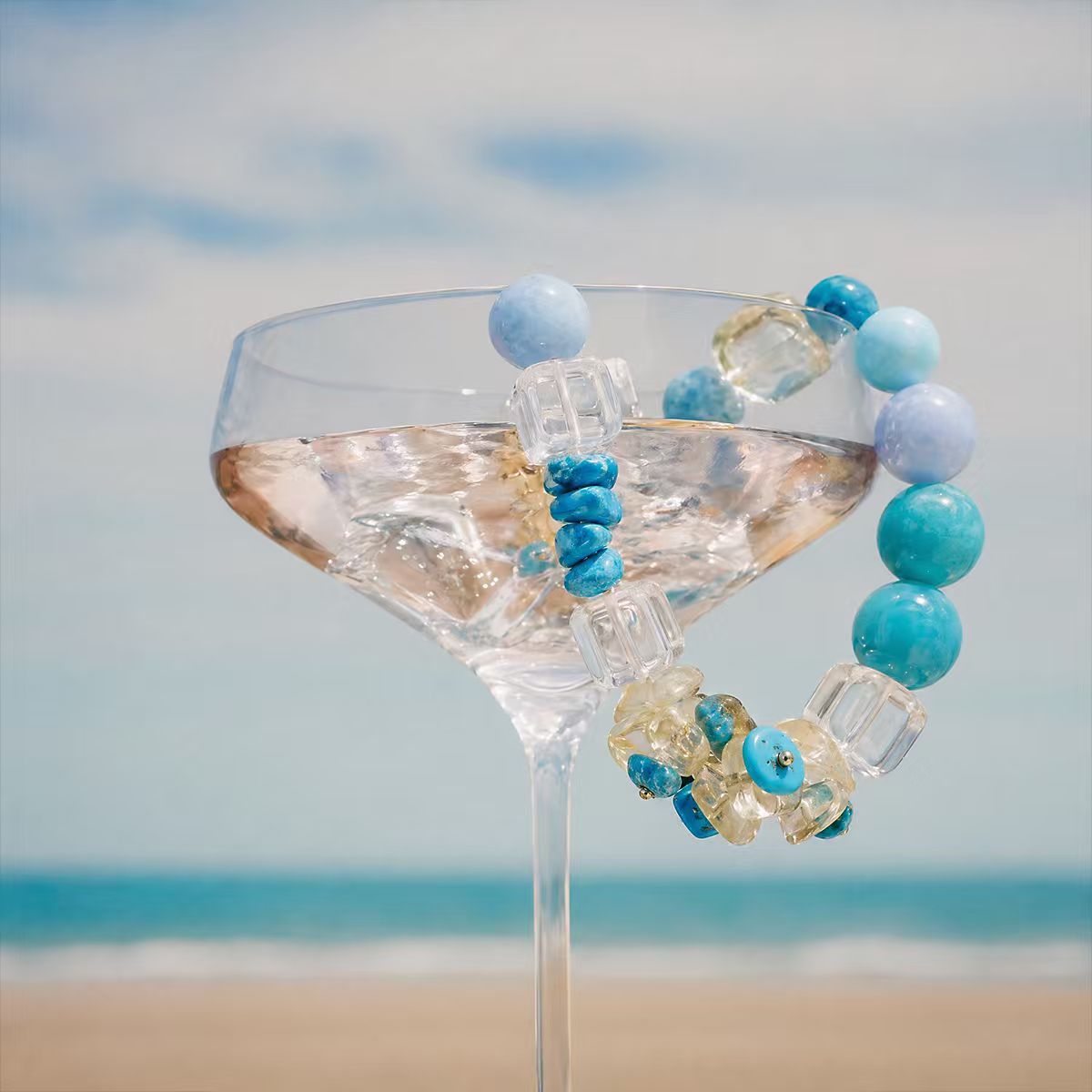 Water | Ease bracelet styled with summer drink on ocean beach background